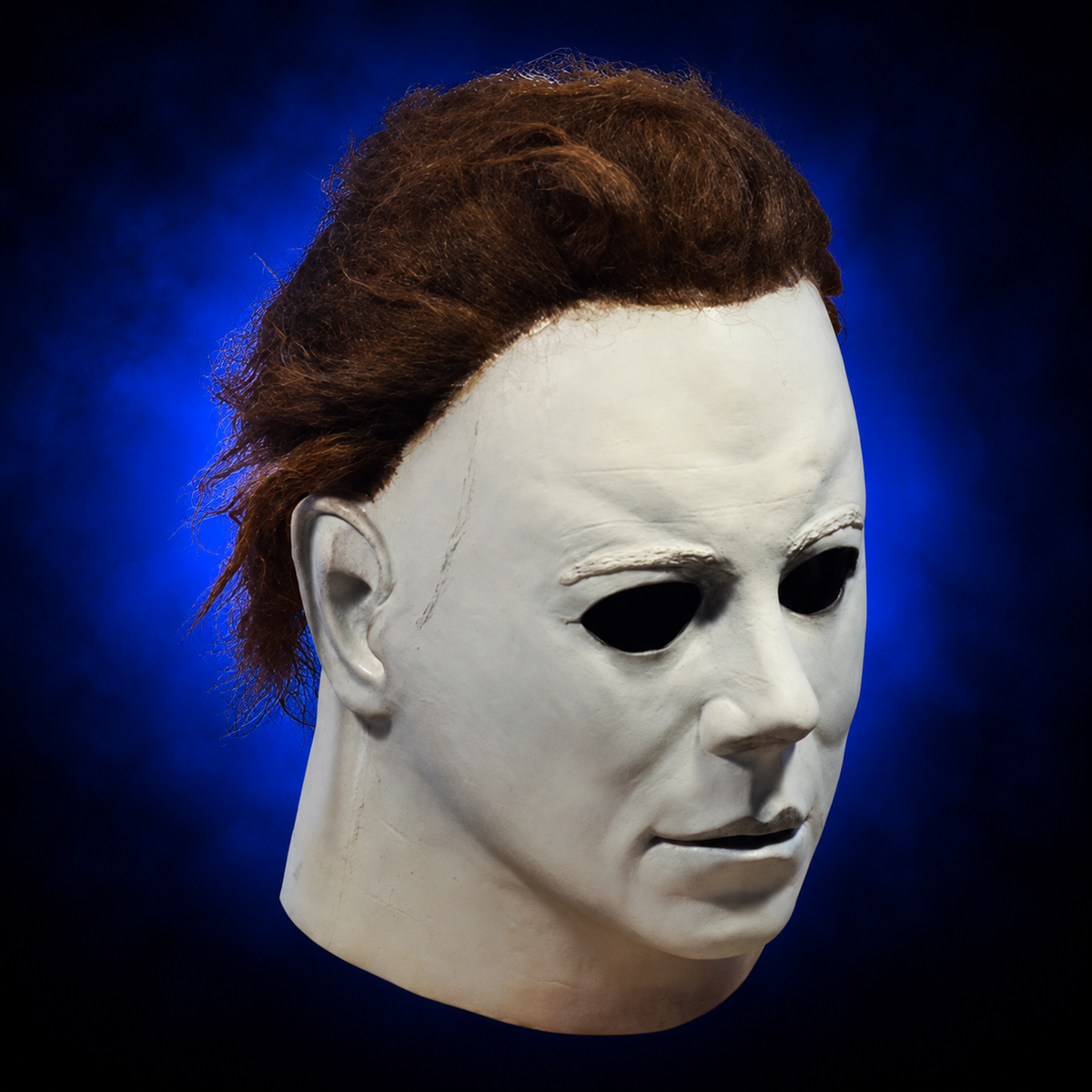 Halloween (1978) Michael Myers mask, right-facing angled view against dark blue radiant background